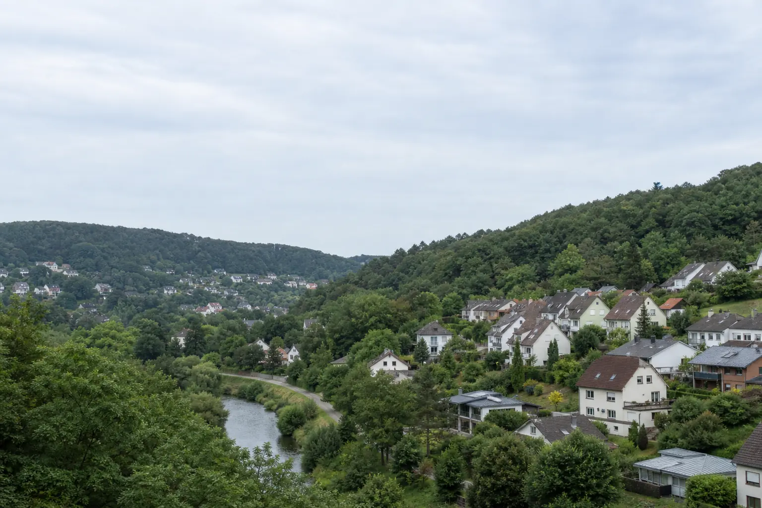 Wohnhäuser in hügeliger, bewaldeter Landschaft im Saarland