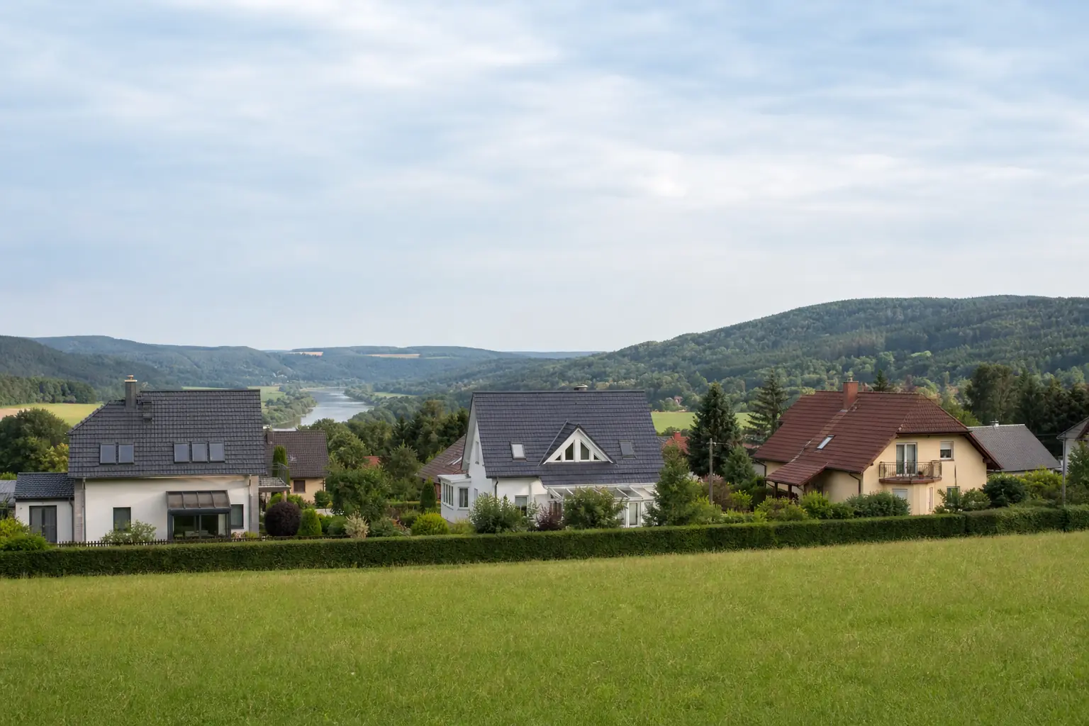 Wohnhäuser vor bewaldeten Hügeln in Sachsen