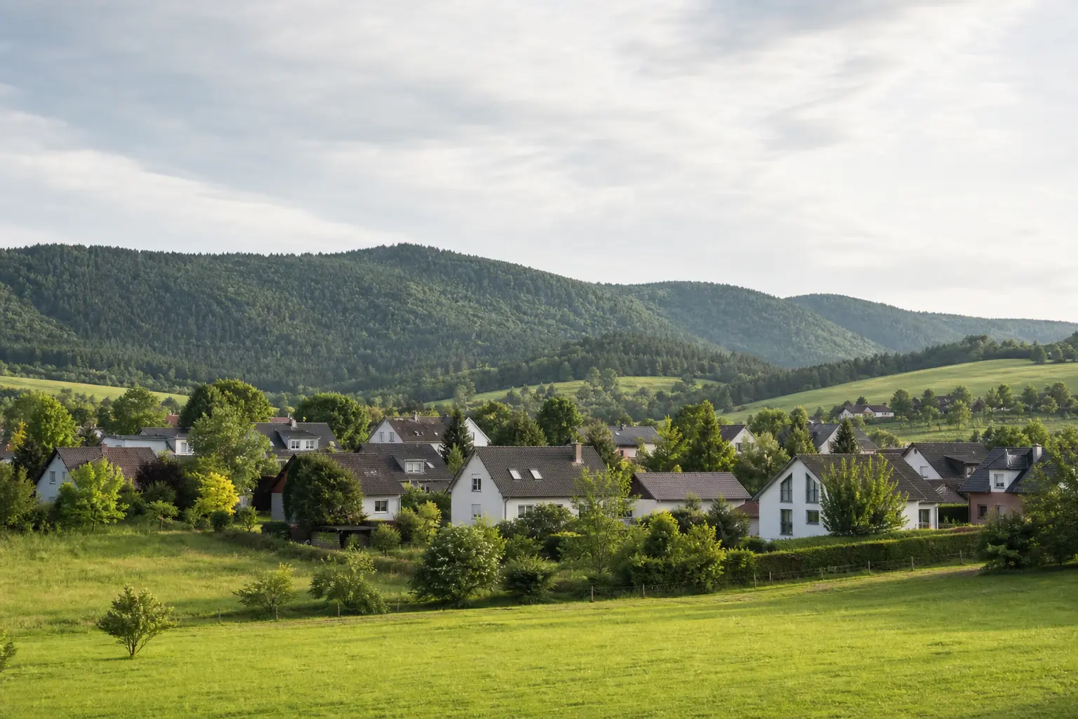 Wohnhäuser vor bewaldeten Höhenzügen in Thüringen
